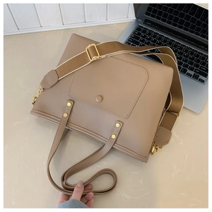 Détail du sac cabas en cuir beige avec large bandoulière textile et métal doré
