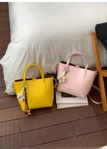 Dettaglio di borse tote in pelle PU gialla e rosa con ciondoli a fiore e nappe lunghe