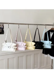 Cinque colori di borse tote in pelle lucida con fibbie appese in uno studio