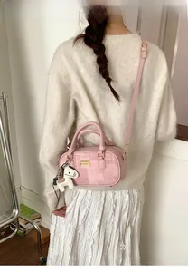 Détail du sac Boston rose avec tissu texturé et breloque cheval porté par un mannequin