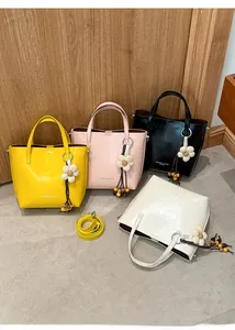 Dettaglio di quattro borse tote colorate in pelle PU con ciondoli a fiore e tracolla