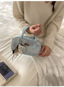 Détail d'un sac à main en denim bleu clair avec plaque dorée et accessoire de poney