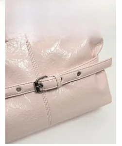 Dettaglio della borsa tote rosa lucida con texture a pieghe e fibbia argentata