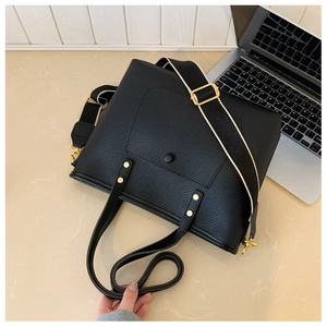 Détail du sac cabas en cuir noir grainé avec ferrures dorées et bandoulière tissée