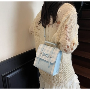 Detail of light blue gingham backpack with bow and thin straps on a model back