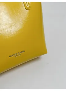 Dettaglio della pelle gialla cerata con logo Fashion & Bags in argento sulla borsa