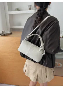 Detail view of cream leather shoulder bag featuring large silver metal ring buckle accents