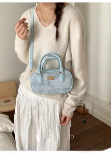 Détail du sac Boston bleu clair avec plaque en métal doré et texture jacquard