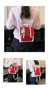 Detailed views of a mini red backpack with white polka dots and fuzzy ball charm pendant