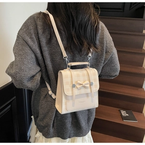 Detail of cream plaid backpack with bow decor and adjustable straps on a model