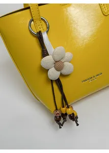 Dettaglio del ciondolo a fiore in velluto beige con perline su borsa in pelle