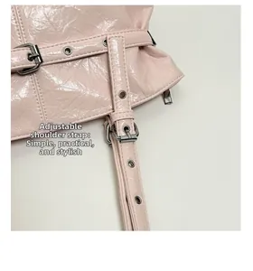 Dettaglio della tracolla regolabile sulla borsa in vernice rosa con occhielli argentati