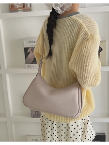 Close-up of a lilac half-moon shoulder bag with lychee texture on a stylish outfit