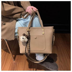 Détail du sac cabas kaki en cuir grainé avec un pendentif en forme d'ours en peluche