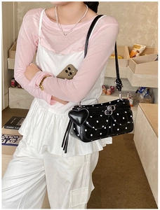Detail of polka dot underarm bag featuring heart tassel and metal buckle front pockets