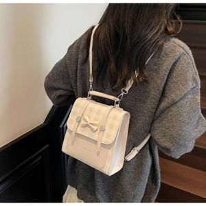 Detail of checkered cream backpack with decorative bow and silver magnetic buckles