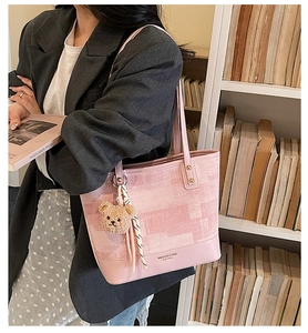 Detailed shot of pink patchwork tote bag with bear charm and brand logo on bottom