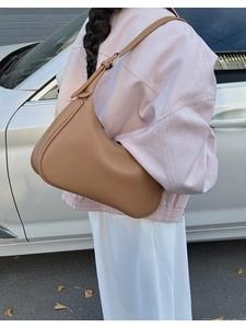 Close-up of camel lychee pattern leather shoulder bag with silver hardware on model