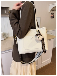 Détail du sac cabas blanc cassé à motif litchi avec breloque ours et sangle réglable
