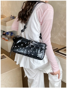 Detailed close-up of a black and white polka dot underarm bag with a heart charm and silver buckles