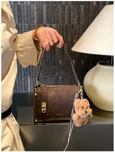 Detailed view of deep brown vintage handbag with gold hardware and plush bear charm