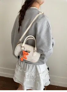 Détail d'un sac Boston crème avec un pendentif cheval porté par un mannequin en vue