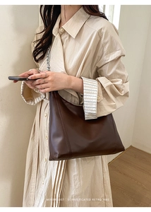 Deep brown leather tote with chunky silver chain strap shown on a beige trench coat