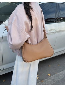 Detail of tan lychee pattern crescent bag with slim adjustable strap on shoulder