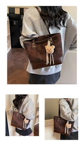 Detail of vintage brown tote bag with square art texture and cute teddy bear charm