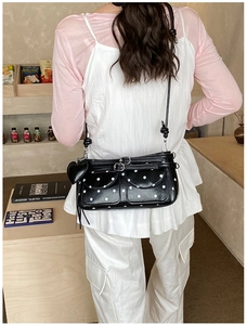 Close-up of black and white polka dot underarm bag with double front pockets and heart charm