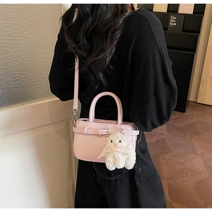 Dettaglio borsa in pelle rosa con ciondolo a coniglietto di peluche e fiocco di perle