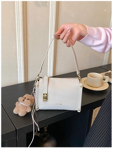 Detail of cream leather handbag with CHUU DON logo and brown teddy bear charm