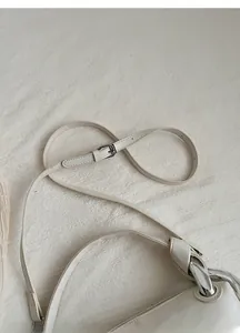 Detail view of adjustable cream leather strap with fine silver metal buckle and ring