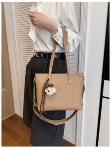 Détail du sac cabas camel en cuir grainé avec un pendentif chien en peluche blanc