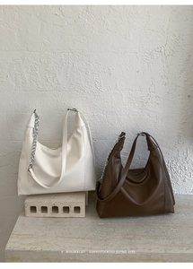 Detail of retro tote bags in cream and dark brown with metal chain and PU texture
