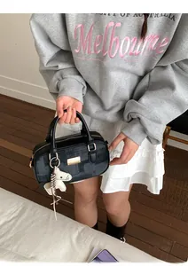 Détails d'un sac Boston noir avec ferrures dorées, texture et breloque petit cheval
