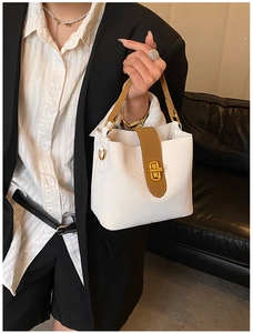 Detail of white leather bucket bag with brown handles and golden turn-lock closure