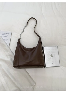 Detail of dark brown leather crescent bag showing spacious interior with an iPad for scale