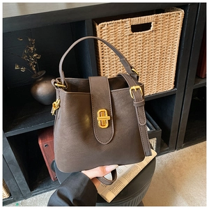 Detail view of brown matte leather bucket bag with gold clasp in vintage home setting