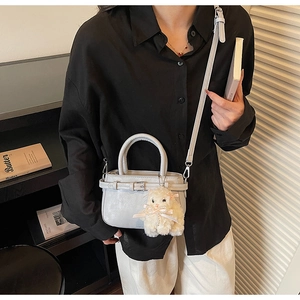 Dettaglio della piccola borsa tote grigio chiaro con ciondolo peluche e tracolla