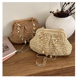 Detail of woven beach bags with gold chains and shell charms on a wooden surface