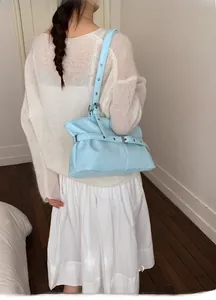 Light blue pleated leather shoulder bag with adjustable strap worn by a model