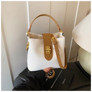 Detail of white and brown contrast leather bucket bag with golden hardware lock