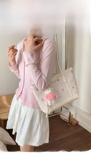 Detail of off-white tote bag with pink bow pattern and cute teddy bear charm accessory