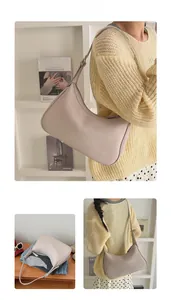 Detail view of beige half-moon underarm bag with lychee texture and slim shoulder strap