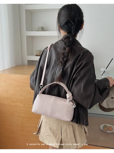 Detail of light pink leather handbag showing knotted handle and adjustable shoulder strap