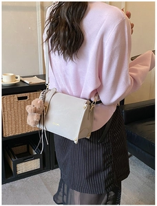 Detail of light gray faux leather crossbody bag with cute plush bear charm and gold logo