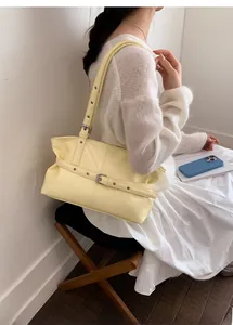Dettaglio della borsa tote in pelle testurizzata giallo chiaro con cinghie decorative