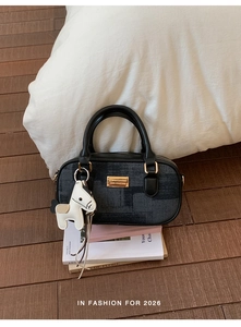 Détail du sac Boston noir avec texture jacquard, logo doré et breloque cheval