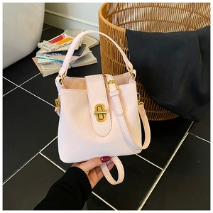 Detail of light pink leather bucket bag featuring elegant gold hardware and a secure clasp